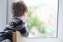The little boy is reading a book. The child sits at the window a stock photo The little boy is reading a book. The child sits at the window a stock photo
