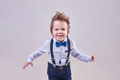 The little boy runs and smiles, wearing a blue bow tie and suspenders royalty free stock photos The little boy runs and smiles, wearing a blue bow tie and suspenders royalty free stock photos