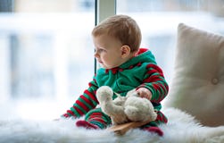 Little boy with teddy bear sits and looks out window. stock photo Little boy with teddy bear sits and looks out window. stock photo