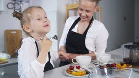 Little caucasian girl with her mother cooking together in the kitchen stock photo Little caucasian girl with her mother cooking together in the kitchen stock photo