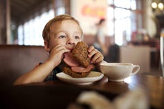 Little child having lunch with sandwich and tea in royalty free stock photo Little child having lunch with sandwich and tea in royalty free stock photo