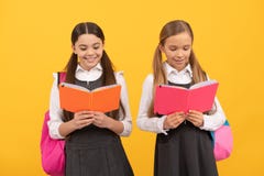 Little children in school uniforms read library books yellow background, reading