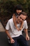 Little Chinese Girl Hanging On Dads Back Stock Image