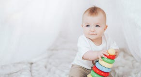 Little Cute Baby Girl With A Toy Pyramid Sitting In White Interior At Home. Royalty Free Stock Photo