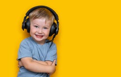 Little Cute Caucasian Blonde Boy In Headphones Posing Happy Smiling Isolated On Yellow Background Stock Photo