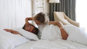 Daughter comes to sleeping father and opens his eyes by hands for wakes him stock video footage Daughter comes to sleeping father and opens his eyes by hands for wakes him stock video footage