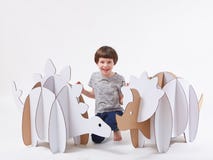 Little dreamer boy playing with a cardboard dinosaurs Triceratops and Stegosaurus. Childhood. Fantasy, imagination.