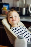 Little funny blonde infant smiling sitting in a nursing chair, looking at you stock images Little funny blonde infant smiling sitting in a nursing chair, looking at you stock images