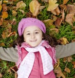 Little Girl At Grass And Leafs In The Park. Royalty Free Stock Image