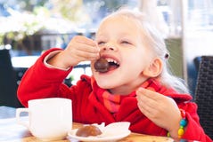 Little Girl Eats Sweets and Drinks Tea in Cafe. royalty free stock image Little Girl Eats Sweets and Drinks Tea in Cafe. royalty free stock image