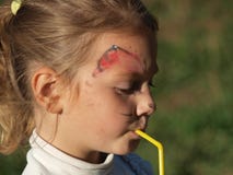 Little girl with face painting drinking through a straw stock photo Little girl with face painting drinking through a straw stock photo