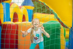 Beautiful little girl having fun peeking from behind the mesh inflatable trampoline. stock photos Beautiful little girl having fun peeking from behind the mesh inflatable trampoline. stock photos