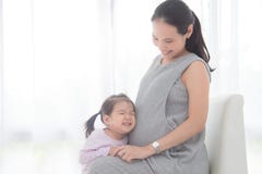 Little girl hugging her pregnant mother belly and smiles stock photo Little girl hugging her pregnant mother belly and smiles stock photo