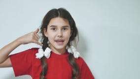 Little girl making a call me sign outdoors. Brunette hispanic girl smiling doing phone gesture with hand and fingers stock footage Little girl making a call me sign outdoors. Brunette hispanic girl smiling doing phone gesture with hand and fingers stock footage