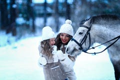 Little girl and mom feeding little horse pony winter. Stock Photos Little girl and mom feeding little horse pony winter. Stock Photos
