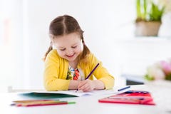 Little girl painting and writing