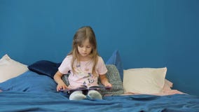 A little girl is reading a book on the bed. stock footage A little girl is reading a book on the bed. stock footage