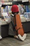 Little girl reading a book in a Japanese bookstore with a violin case on her back stock image Little girl reading a book in a Japanese bookstore with a violin case on her back stock image