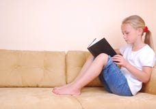 Little girl reading book on sofa