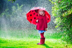 Little girl in red jacket playing in autumn rain
