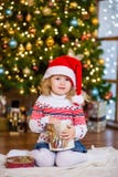 Little girl in red santa hat holding christmas gift box Stock Photos Little girl in red santa hat holding christmas gift box Stock Photos