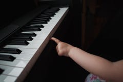 Little girl`s hand next to the piano. A small finger tries to press the keys. No face. Close up. stock photography Little girl`s hand next to the piano. A small finger tries to press the keys. No face. Close up. stock photography