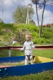 A little girl is standing in a sandbox with her eyes squeezed from the sun stock images A little girl is standing in a sandbox with her eyes squeezed from the sun stock images