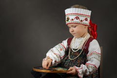Little girl in the traditional russian sarafan during embroidering.