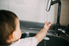 Little girl washes her hands in the kitchen by herself royalty free stock photography Little girl washes her hands in the kitchen by herself royalty free stock photography