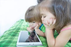 Little girls looking on pad lying on bed at home. Children time spending. Kids using tablet royalty free stock image Little girls looking on pad lying on bed at home. Children time spending. Kids using tablet royalty free stock image