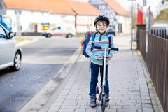 Little kid boy in helmet riding with his scooter in the city stock photography Little kid boy in helmet riding with his scooter in the city stock photography