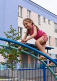 A little smiling girl using the sports equipment in a playground of an apartment house& x27;s court yard stock photo A little smiling girl using the sports equipment in a playground of an apartment house& x27;s court yard stock photo