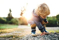 A little toddler boy picking up stones in nature at sunset. Copy space. stock images A little toddler boy picking up stones in nature at sunset. Copy space. stock images