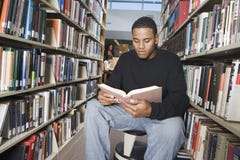 Livre de lecture d'homme dans la bibliothèque image stock Livre de lecture d'homme dans la bibliothèque image stock