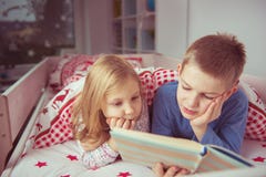Livre de lecture heureux de deux enfants d'enfant de mêmes parents dans le lit superposé sous le blanke Images libres de droits Livre de lecture heureux de deux enfants d'enfant de mêmes parents dans le lit superposé sous le blanke Images libres de droits