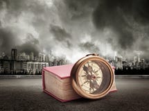 Livre et boussole sur la vue de la ville en ciel orageux images stock Livre et boussole sur la vue de la ville en ciel orageux images stock