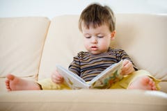 Livro de leitura bonito do rapaz pequeno no sofá Foto de Stock Livro de leitura bonito do rapaz pequeno no sofá Foto de Stock