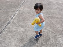 Little Asian baby girl holding her favorite doll while learning to walk by herself stock image Little Asian baby girl holding her favorite doll while learning to walk by herself stock image