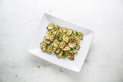lo zucchini freschi del taglio Zucchini arrostito con la spezia rossa sul piatto bianco immagine stock libera da diritti lo zucchini freschi del taglio Zucchini arrostito con la spezia rossa sul piatto bianco immagine stock libera da diritti