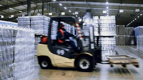 loader on the background of a huge industrial food warehouse with plastic PET bottles with beer, water, drinks.