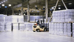 loader on the background of a huge industrial food warehouse with plastic PET bottles with beer, water, drinks.