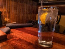 Lodowa woda z cytryną i słomą na stole w restauracyjnym położeniu fotografia stock Lodowa woda z cytryną i słomą na stole w restauracyjnym położeniu fotografia stock