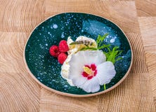 Lody z kwiatem Błękitny round ceramiczny talerz z białym lody Piękny zimny deser na drewnianym zdjęcie royalty free Lody z kwiatem Błękitny round ceramiczny talerz z białym lody Piękny zimny deser na drewnianym zdjęcie royalty free