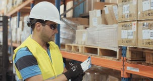 Logistiekarbeider het inspecteren punten in een groot pakhuis stock video Logistiekarbeider het inspecteren punten in een groot pakhuis stock video