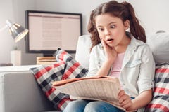 Loisirs de petite fille à la maison se reposant lisant des nouvelles choquées image stock Loisirs de petite fille à la maison se reposant lisant des nouvelles choquées image stock