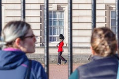 Back view of two tourists watching a sentry of Grenadier Guards patrolling outside Buckingham Palace stock images Back view of two tourists watching a sentry of Grenadier Guards patrolling outside Buckingham Palace stock images