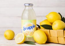 LONDRES, REINO UNIDO - 3 DE SETEMBRO DE 2018: Garrafa do suco de limão de Snapple no fundo de madeira com os limões frescos na ce imagens de stock LONDRES, REINO UNIDO - 3 DE SETEMBRO DE 2018: Garrafa do suco de limão de Snapple no fundo de madeira com os limões frescos na ce imagens de stock