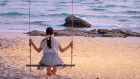 Lonely Asian woman sitting on swing at the beach stock photo Lonely Asian woman sitting on swing at the beach stock photo