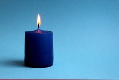 Lonely candle lit on a blue background stock images Lonely candle lit on a blue background stock images