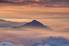 Lonely conical shaped mountain above morning mist and clouds stock photography Lonely conical shaped mountain above morning mist and clouds stock photography